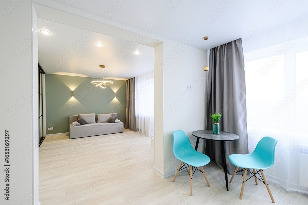 Fototapeta premium modern interior featuring an open-plan living area with a sofa, a dining nook with two chairs, and sleek design elements.