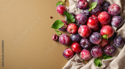 Fresh Ripe Plums Arranged on Beige Background with Textile for Culinary and Healthy Food Concepts