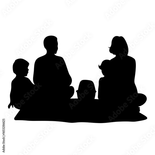 Silhouette of a family sitting around a picnic basket on a blanket