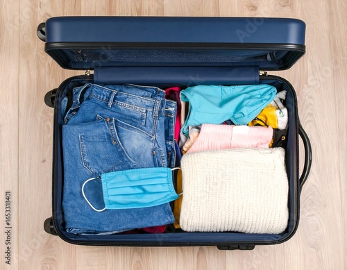 Open suitcase filled with clothes and a mask (1)