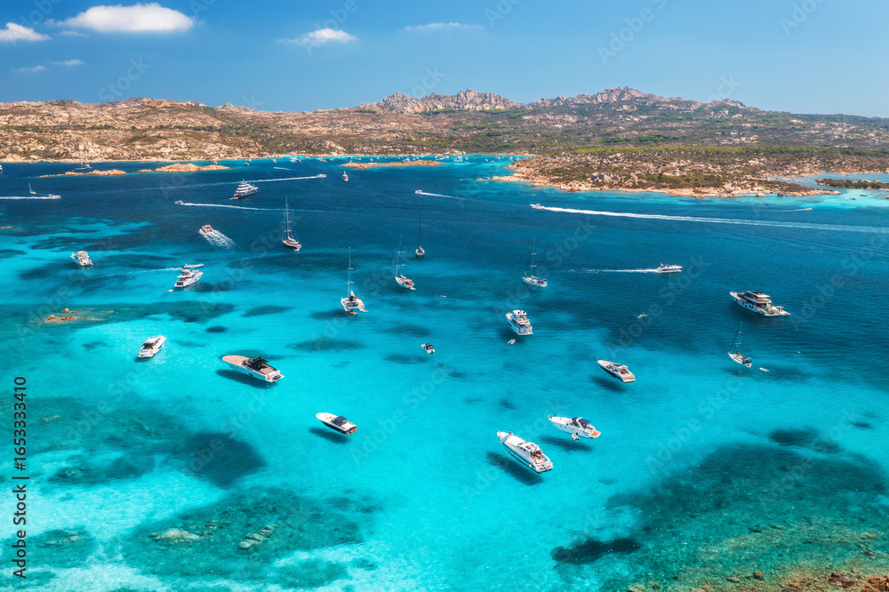 Obraz premium Aerial view of luxury yachts and boats on blue sea, beautiful island, mountain on summer sunny day. Sandy beach, rocky sea coast, azure transparent water in Sardinia, Italy. Top drone view. Seascape