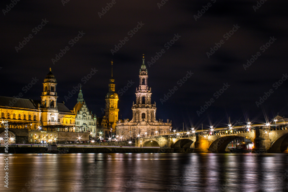 Fototapeta premium Night view of Dresden, Germany, featuring illuminated baroque architecture and a historic bridge over the Elbe River.