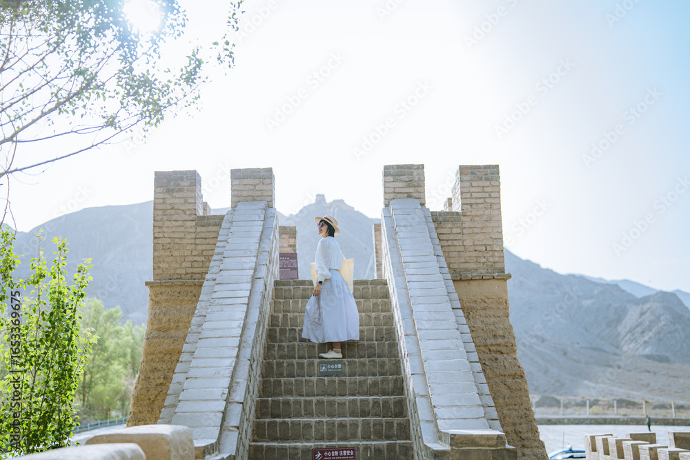 Naklejka premium woman traveling in Overhanging Great Wall in Jiayuguan, China. The west end of the Great Wall of China in Summer. 