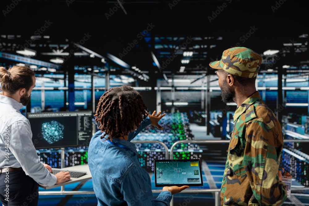 Obraz premium Army operators in server hub using device to run drone control software, looking at mission map overlay via satellite imagery. Diverse military experts develop national defense strategy.