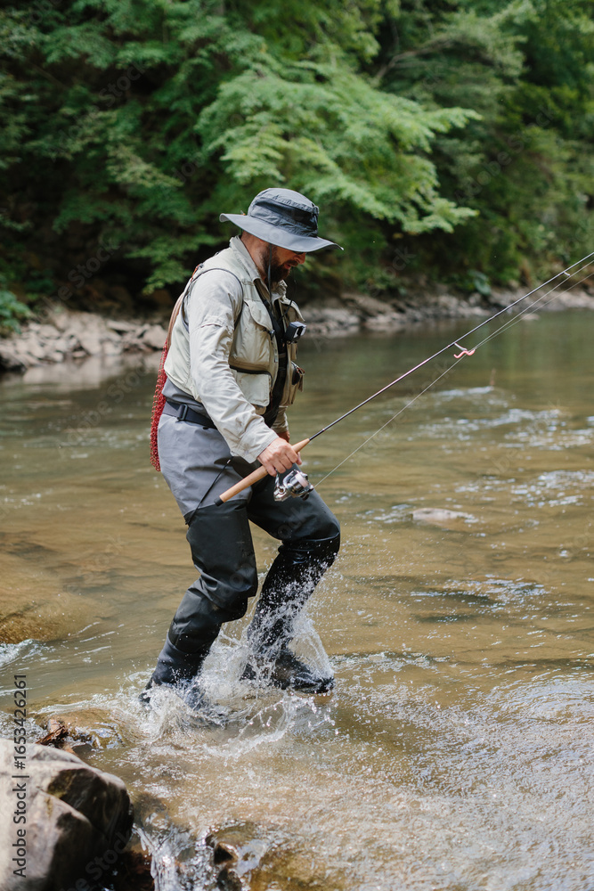 Fisherman wading in river casting line for trout fishing Fisherman wading in river casting line for trout fishing