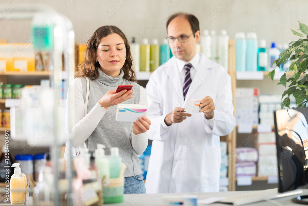 Fototapeta premium Experienced pharmacist and his assistant check data on medical drugs on the Internet