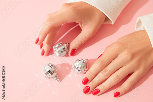 Womans hands with red manicure on pink background. Beauty salon concept