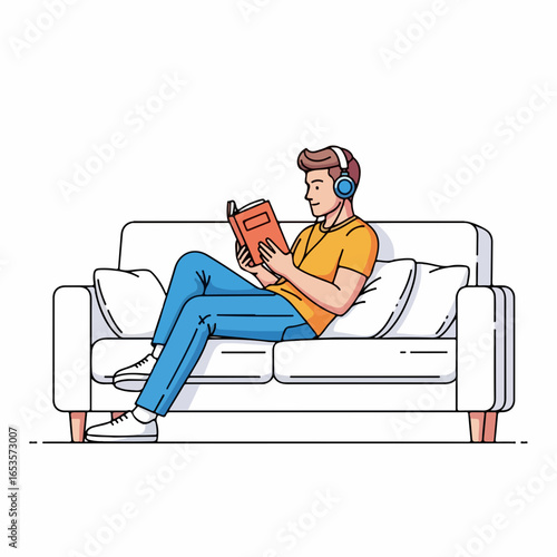 Young man relaxing on couch, reading book, listening to music with headphones