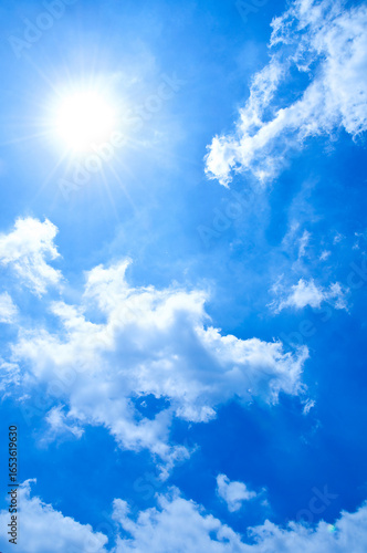 Bright Summer Sun and Clear Blue Sky with Fluffy White Clouds. A radiant summer sun shines brilliantly in a deep blue sky, casting warm light over fluffy white clouds. boundless energy of a sunny day.