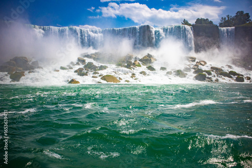 Fotografie The gushing turquoise water from the Niagara falls with blue sky and white cloud