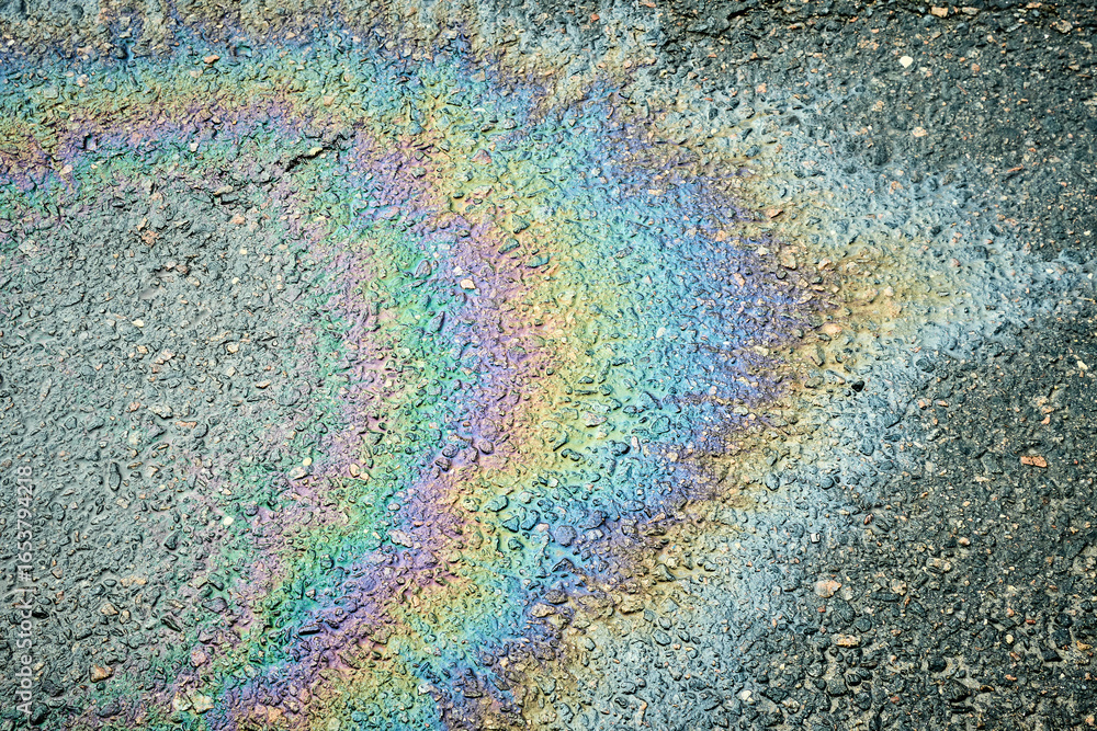 Fototapeta premium Iridescent gasoline spill creating a rainbow effect on a wet asphalt road