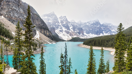 Lac Moraine turquoise entouré de montagnes enneigées et forêt de sapins