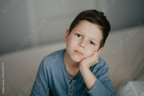 A preschool boy in a blue T-shirt is boring