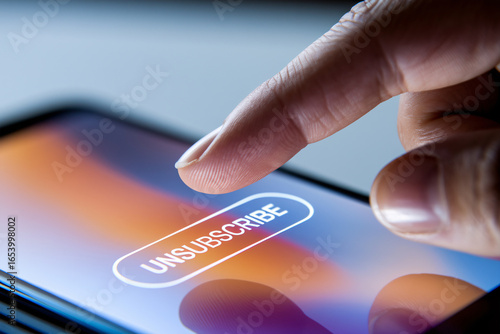Close up of person's finger hovering over unsubscribe button on mobile phone screen