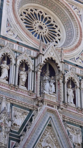 Close up vertical view of Florence Cathedral facade with rose window and statues 