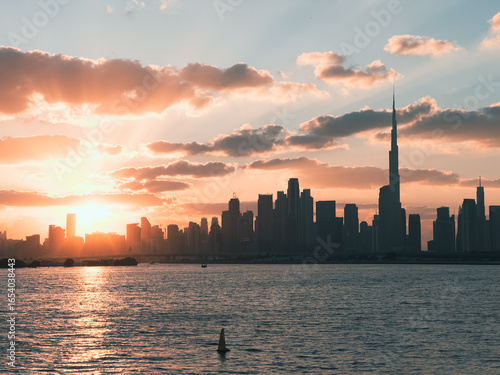 Canvas Print Dubai skyline at golden hour with dramatic sunset sky and calm water waves, duba