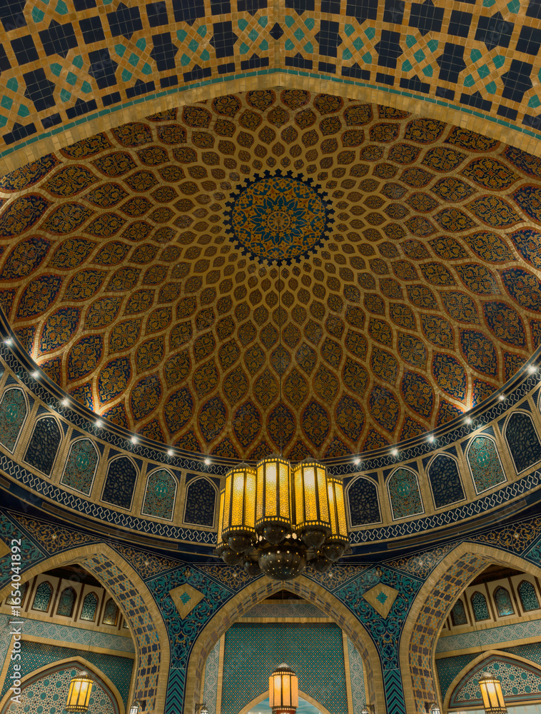Naklejka premium Opulent chandelier on patterned Islamic dome ceiling with arabesque geometric design