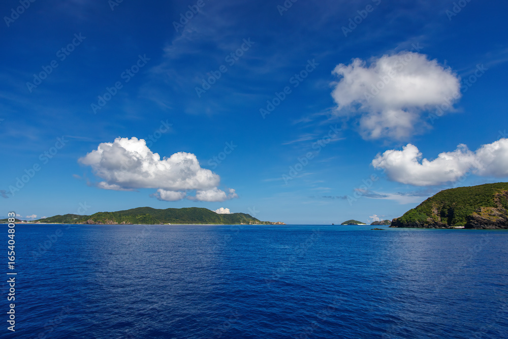 Fototapeta premium 慶良間諸島の座間味島等へゆく高速ジェットフェリー。 クイーンざまみ3号。 慶良間諸島に到着した。座間味島や阿嘉島、無人島の安室島、嘉比島、安慶名敷島などが見える。 ヨットやクルーズ船とすれ違う。 島には白砂のビーチや緑の森、灯台もある。 沖縄県島尻郡慶良間諸島-2025/6/27 