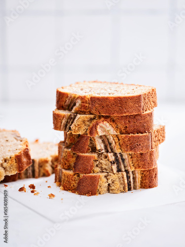 Freshly baked banana bread sits in thick, even slices on a white background. Each slice showcases the moist texture, making it ideal for breakfast or a delightful snack
