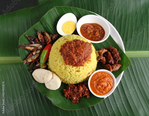 Traditional nasi lemak with sambal and rice served on banana leaf.