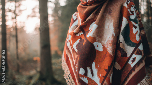 Woven scarf featuring endangered animal motifs, set against a misty forest backdrop.