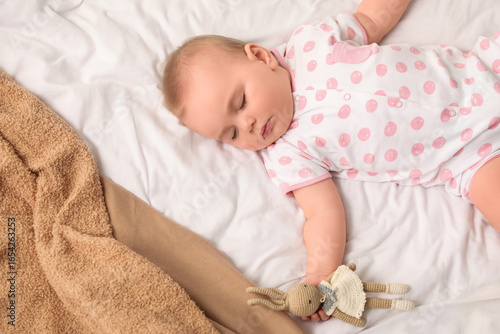 Cute sleeping little baby with bunny toy on bed at home