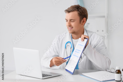 Young male doctor explaining medical information to patient on laptop in mode...