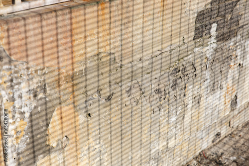 Vintage aged wall with texture showing effects of weather and time and shadow of a fence. Background photo 