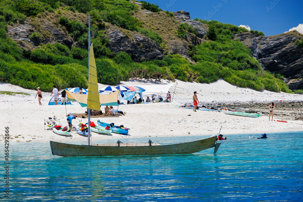 Fototapeta premium 無人島の嘉比島が見える。 白砂のビーチには観光客が上陸している。 パラソルやボート、サバニ(沖縄特有の双胴船)も見える。 船上からも水底の様子が見える。 素晴らしい透明度。 沖縄県島尻郡慶良間諸島座間味島嘉比島-2025/6/27