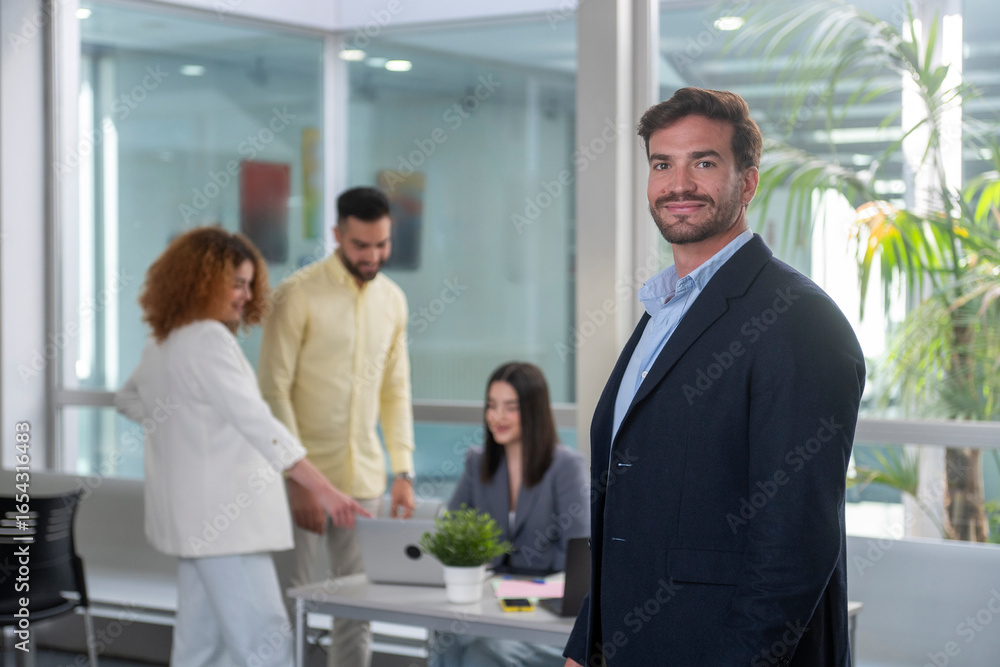 Fototapeta premium Portrait of confident businessman with coworkers collaborating in modern office