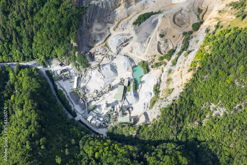 Aerial view of a quarry with contrasting textures of raw stone and lush green forests surrounding, Weizklamm, Steiermark, Austria.