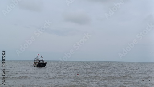 Tableau sur toile Lonely fishing boat adrift on a gray, overcast ocean.