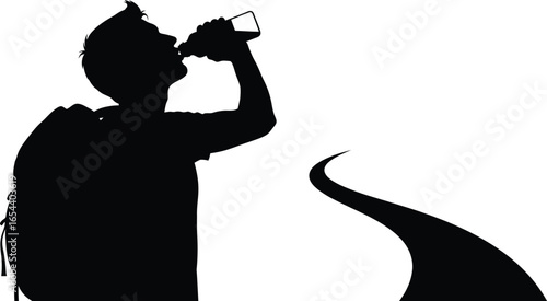 Silhouette of a man drinking water from a bottle while hiking with a backpack a road