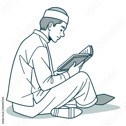 Young muslim boy wearing a kufi hat reads a book while sitting cross legged on the floor