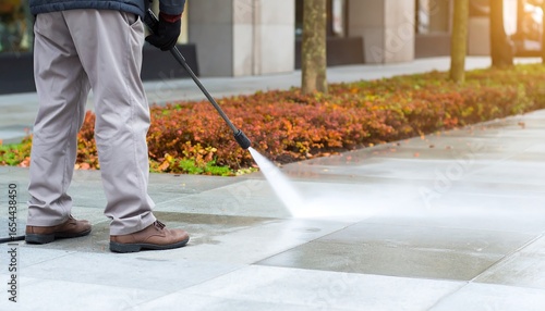 Individual power washing a paved walkway.