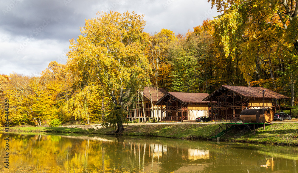 Obraz premium autumn landscape with guest houses in the forest by the lake on a sunny day