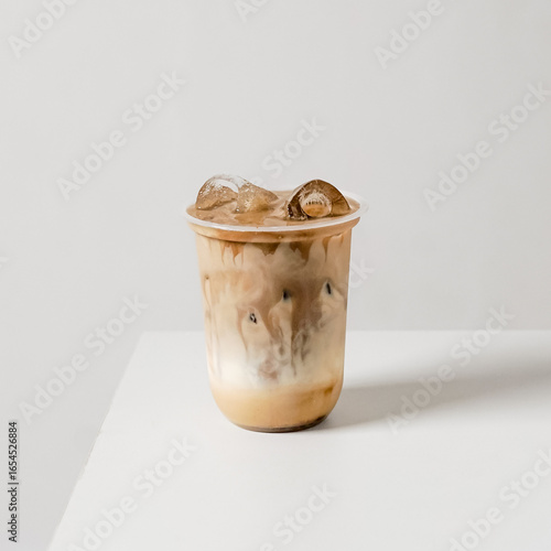 Layered iced latte with milk and espresso gradient in a plastic cup on white background. Modern product photo for cafe menu, packaging, mockups, and delivery apps.