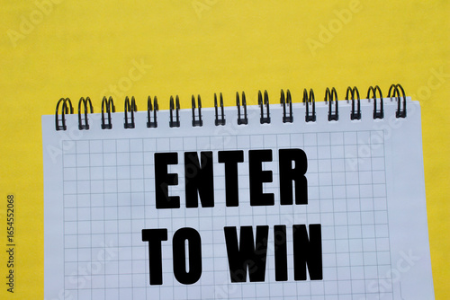 Valokuva Enter to win message written on notebook page on yellow background