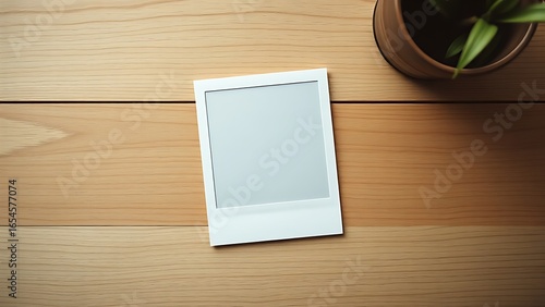 Sticker A vintage polaroid frame on a wooden table, captured from an overhead angle in minimalist style