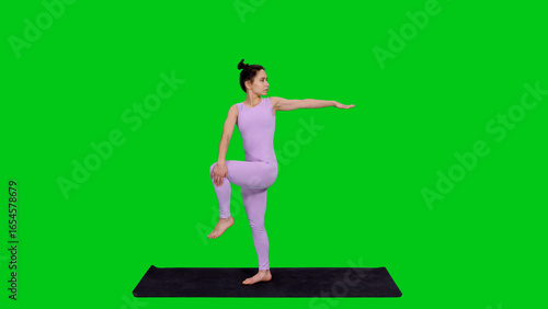Young fit woman practicing yoga posture on mat isolated on green chroma key  background