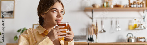 Принти на полотні A young beautiful woman savors her tea while relaxing in a charming home kitchen atmosphere