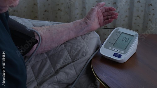 Elderly person checking blood pressure in a home setting. Concept of autonomous monitoring of medical conditions through convenient solutions.