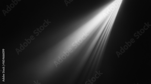 Diagonal beam of white light on black background. Minimalistic composition with slightly diffused soft rays of light.