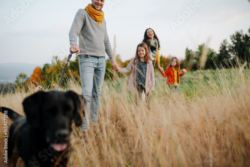 Family took dog on walk in autumn nature.