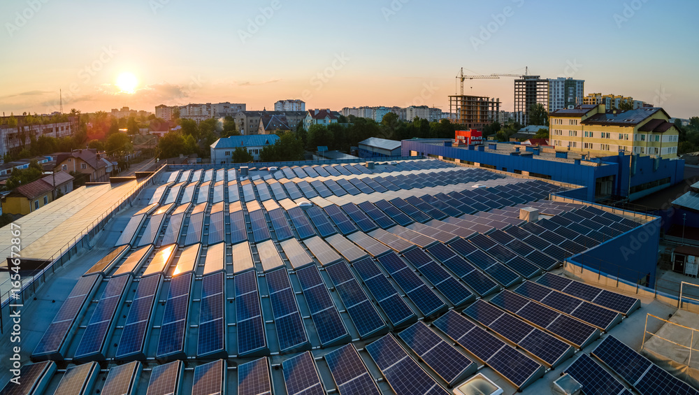 Obraz premium Blue photovoltaic solar panels mounted on building roof for producing clean ecological electricity at sunset. Production of renewable energy concept