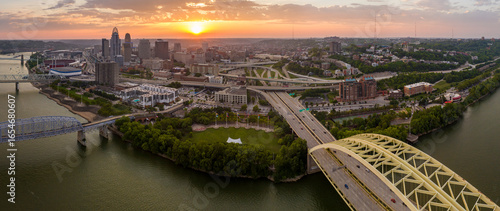 Fototapeta Naklejka Na Ścianę i Meble -  Night urban landscape of downtown district of Cincinnati city in Ohio, USA. Skyline with driving cars on bridge and brightly illuminated high skyscraper buildings in modern American megapolis
