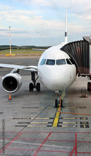 Airplane with passenger jet bridge attached. View from the airport window