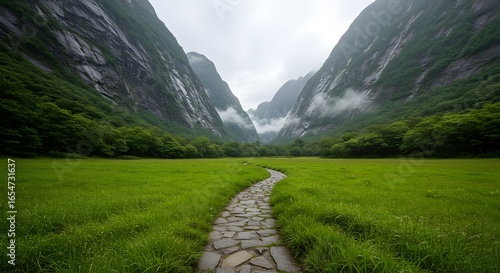 Fototapeta Naklejka Na Ścianę i Meble -  Serene Stone Path Winding Through Lush Green Valley Enveloped by Majestic Mountains and Misty Peaks