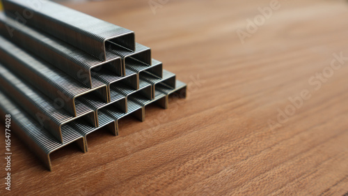 Close up of metal staples stacked in pyramid shape on wooden surface