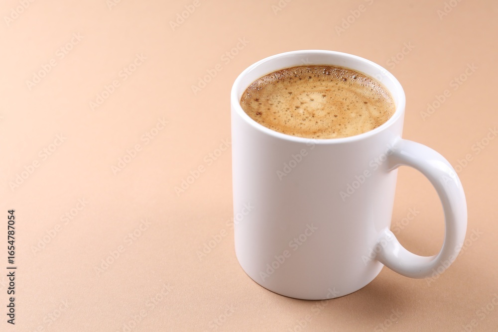 Fototapeta premium Aromatic coffee in cup on beige background, closeup. Space for text